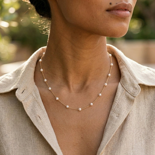 Woman wearing a pearl necklace with a blurred natural background