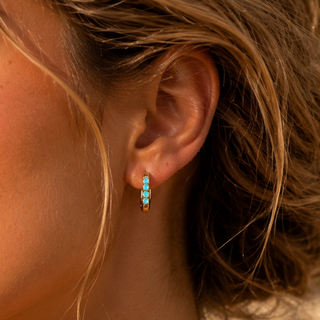 Close-up of a woman wearing turquoise earrings with a blurred background