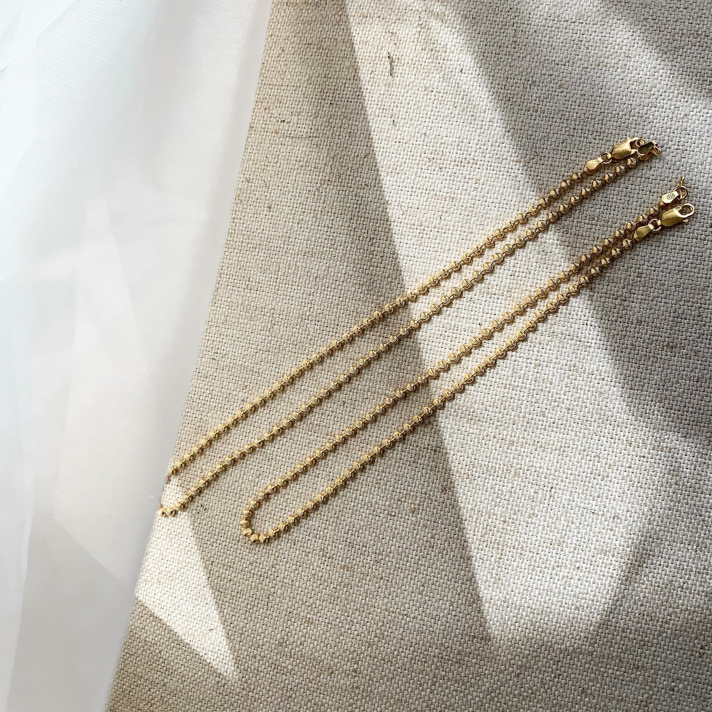 Colliers de chaîne de brad en croissant de lune en or 14 carats posés à plat photo kemmi collection bijoux boho